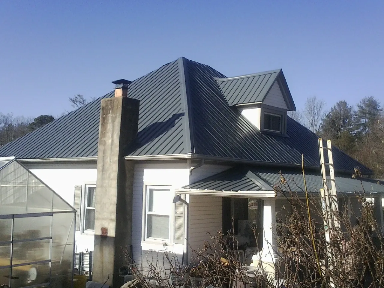 Dark blue standing seam metal roof on a white farmhouse with dormer — Slate & Tile Roof Repair by Roofing Brothers in Glen Alpine
