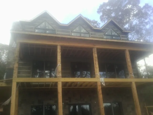Dormers and porch framing on a large log home under construction — Roof Coating work by our crew in Glen Alpine
