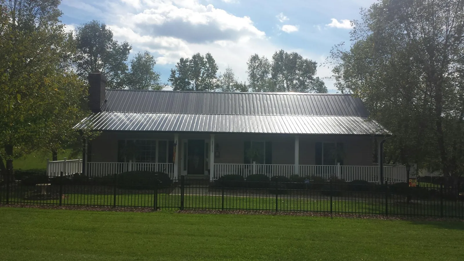 Gray metal roof on a brick ranch with a full width front porch — Gutter Guard Installation work by our crew in Glen Alpine