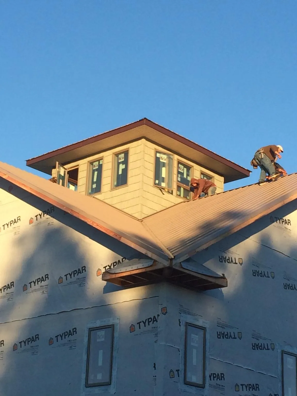 Roofers working around a rooftop cupola on a new metal roof at sunset — Roof Waterproofing in Glen Alpine by Roofing Brothers